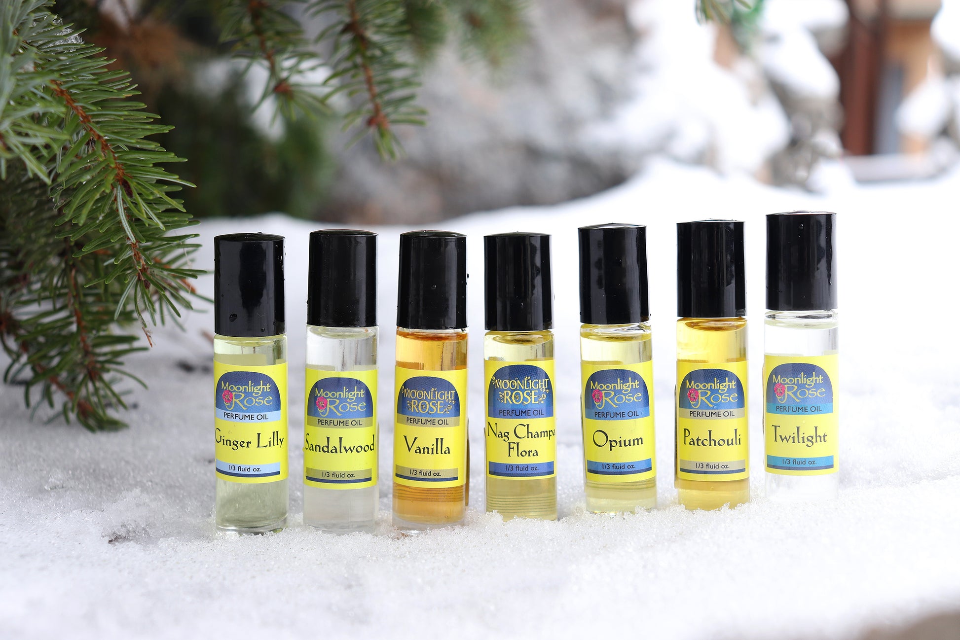 Set of small Moonlight Rose Perfume oil bottles with labels on a snowy background